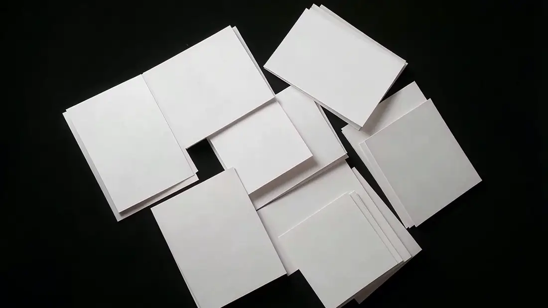 A scattered pile of blank photo prints sorting itself into neat stacks